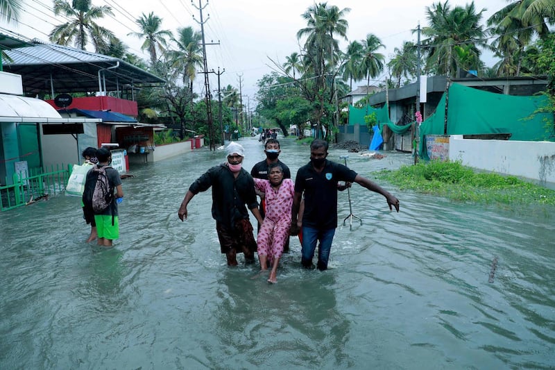 Police and rescue workers help a local resident along a flooded street in a coastal area of Kochi after Cyclone Tauktae caused heavy rain. AFP