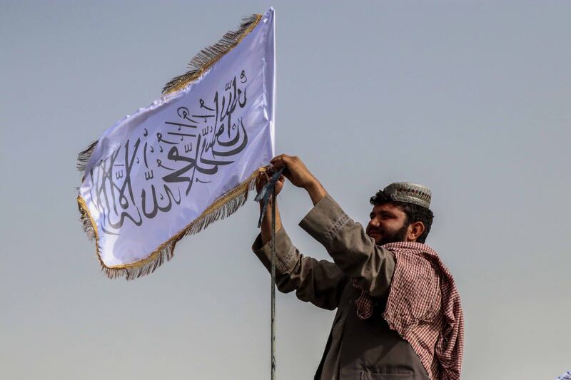 A Taliban fighter raises their flag on a vehicle as they patrol in Kandahar.
