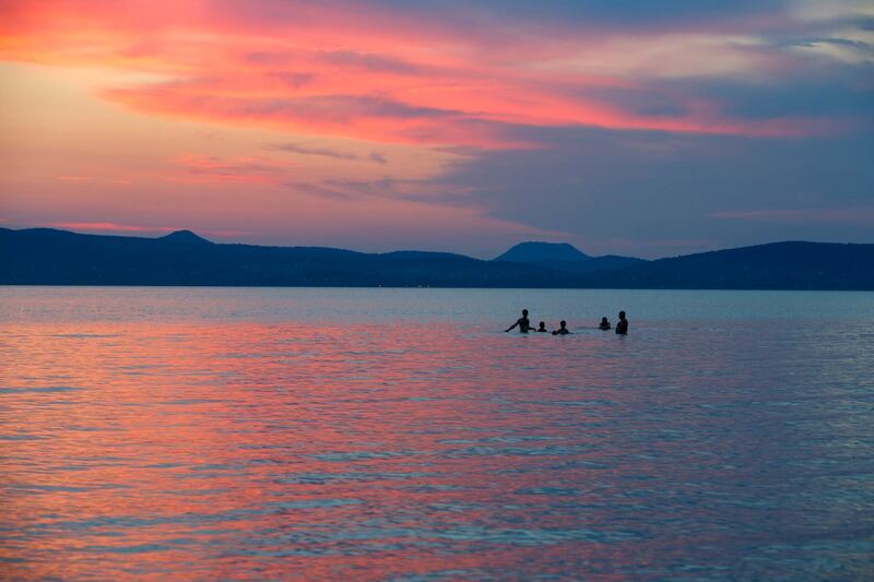 People bathe in Lake Balaton at sunset near Balatonboglar, Hungary. Gyorgy Varga/EPA