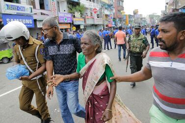 An elderly woman is helped near St Anthony's Shrine after a blast in Colombo, Sri Lanka, on Easter Sunday. Eranga Jayawardena / AP