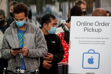 A customer has his temperature taken while in line outside an Apple store to pick up the new iPhone 12. Reuters