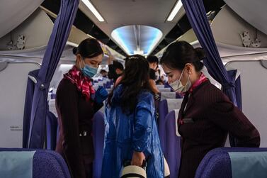 Cabin crew with protective masks welcome passengers on board a flight in Bangkok. AFP