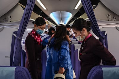 Hostesses with protective masks welcome passengers board their flight to Shanghai at Suvarnabhumi airport in Bangkok, on February 24, 2020.
 The novel coronavirus has spread to more than 25 countries since it emerged in December and is causing mounting alarm due to new outbreaks in Europe, the Middle East and Asia. / AFP / Hector RETAMAL
