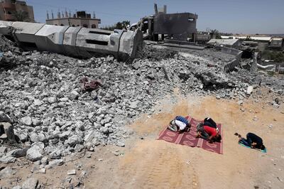 TOPSHOT - Palestinian Muslim worshippers pray near the rubble of a destroyed mosque in Beit Lahia, in the northern Gaza Strip, on May 27, 2021. A ceasefire was reached late last week after 11 days of deadly violence between Israel and the Hamas movement which runs Gaza, stopping Israel's devastating bombardment on the overcrowded Palestinian coastal enclave which, according to the Gaza health ministry, killed 248 Palestinians, including 66 children, and wounded more than 1,900 people. Meanwhile, rockets from Gaza claimed 12 lives in Israel, including one child and an Israeli soldier. / AFP / THOMAS COEX
