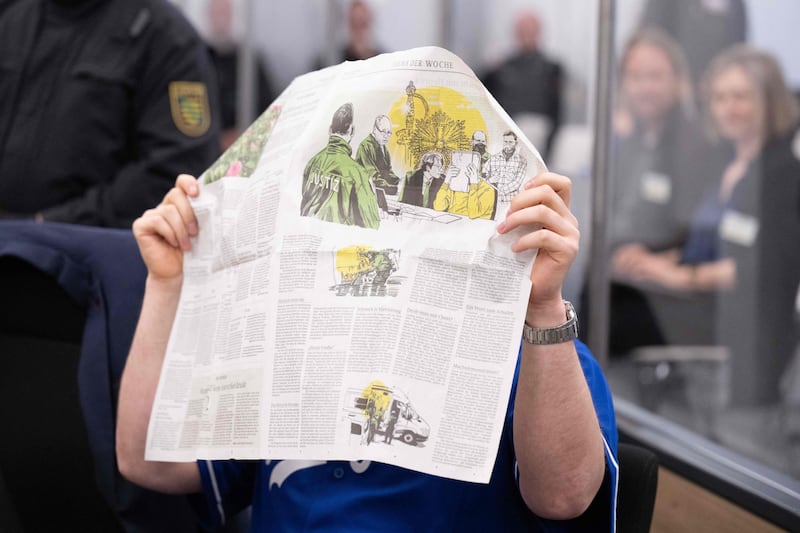 A defendant hides his face behind a newspaper reporting on his trial. AFP