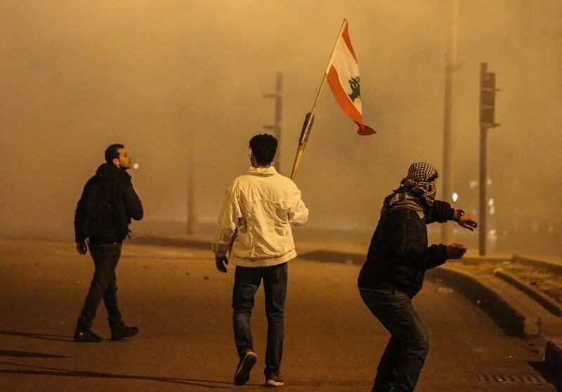 Protesters wave the Lebanese flag in front of riot police during clashes in Beirut.  EPA