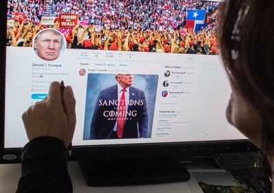 An illustration shows a woman looking at the Twitter page of US President Donald Trump reading "Sanctions Are Coming November 5" at an office in Washington, DC on November 2, 2018. - The United States will add 700 individuals and entities to its Iran blacklist and pressure the global SWIFT banking network to cut off Tehran when expanded sanctions are put in place next week, US officials said November 2, 2018. The sanctions come six months after President Donald Trump withdrew from the 2015 nuclear deal struck between world powers and Iran. (Photo by STF / AFP)