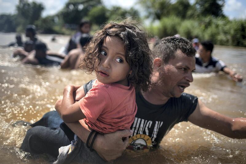 Luis Acosta holds 5-year-old Angel Jesus, both from Honduras, as a caravan of migrants from Central America en route to the United States crossed through the Suchiate River into Mexico from Guatemala in Ciudad Hidalgo, Mexico, October 29, 2018. Picture taken October 29, 2018. REUTERS/Adrees Latif/File Photo   SEARCH "POY DECADE" FOR THIS STORY. SEARCH "REUTERS POY" FOR ALL BEST OF 2019 PACKAGES. TPX IMAGES OF THE DAY.