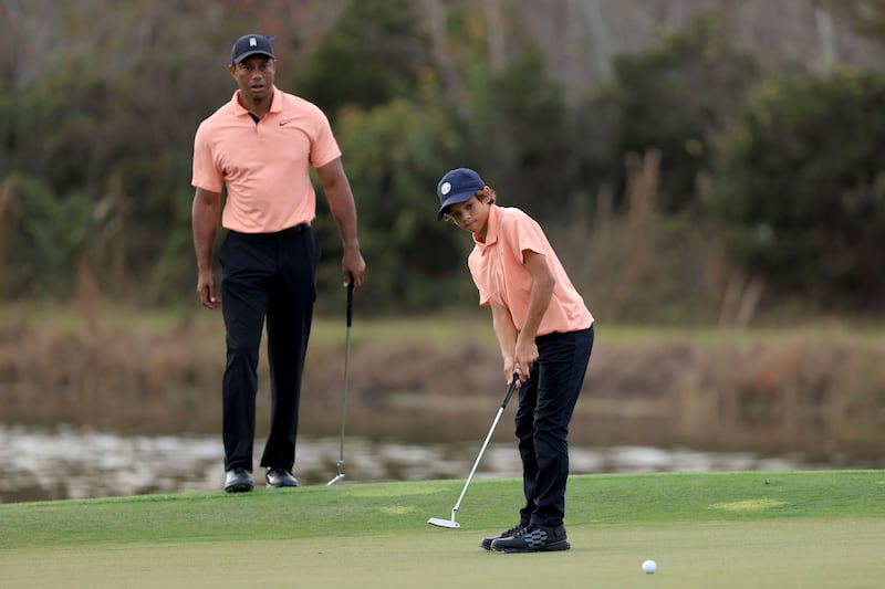 Charlie Woods plays a shot on the ninth hole as Tiger Woods looks on. AFP