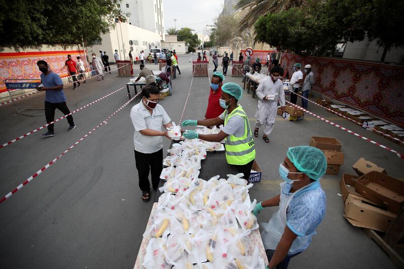 Volunteers wearing protective face masks and gloves hand out iftar meals in Manama, Bahrain. Reuters