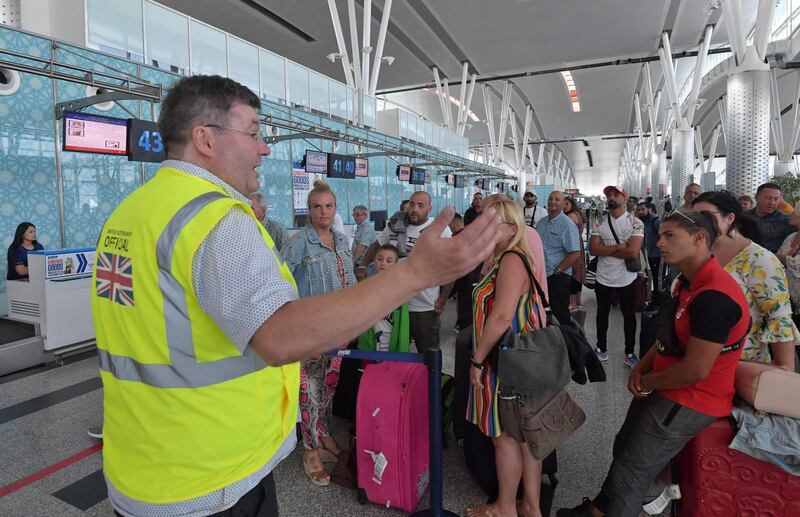 A British government official speaks to tourists, flying with Thomas Cook, as they queue at the Enfidha International airport, on the outskirts of Sousse south of the capital Tunis. AFP