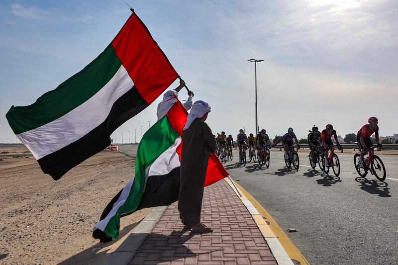 UAE flags fly as the peloton passes during the first stage of the UAE Cycling Tour from Al Dhafra Castle to Qassar Al Mighayra St in Al Mirfa in Abu Dhabi. AFP