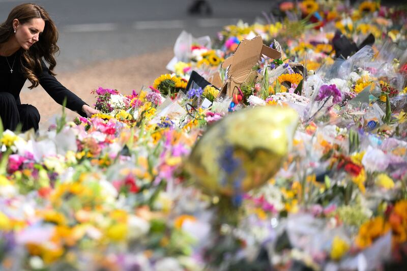 The Princess of Wales looks at floral tributes. AFP