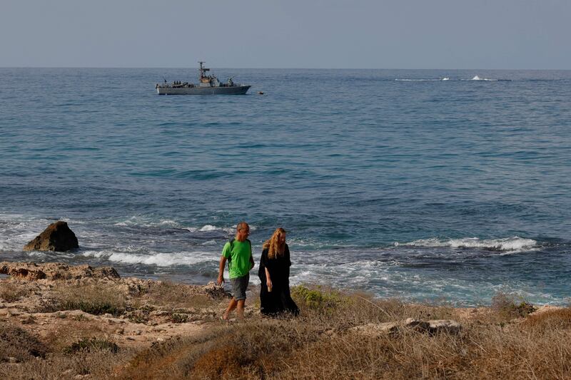 Israelis walk along the beach as a navy vessel patrols the Mediterranean waters off Rosh Hanikra, known in Lebanon as Ras Al Naqura, on Friday. AFP