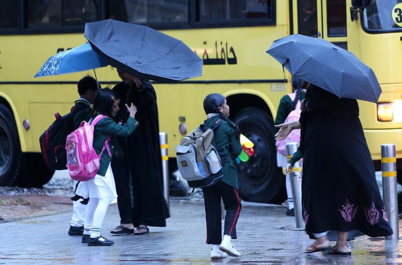 Children board the school bus in the rain at Discovery Gardens in Dubai. Pawan Singh / The National

