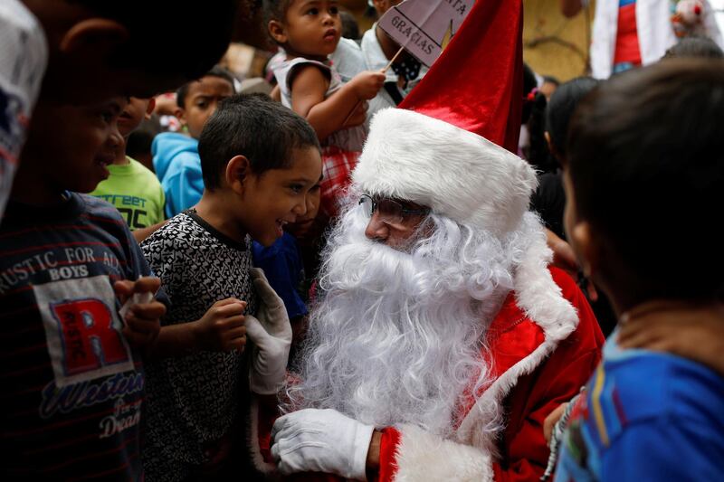 Richard Gamboa, dressed up as Santa Claus, talks with a boy during the 'Santa en las calles' (Santa in the streets) event donating toys, food, and clothes at the slum Cota 905 in Caracas, Venezuela. Reuters