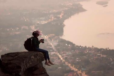 Tourist with backpack relaxing on top of a mountain and enjoying sunrise. Getty Images