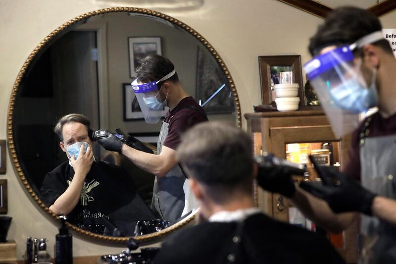 Vin Norton gets a haircut by barber Cristian Lopez at Barber Walter's barbershop, as they both wear masks out of concern for the coronavirus. AP