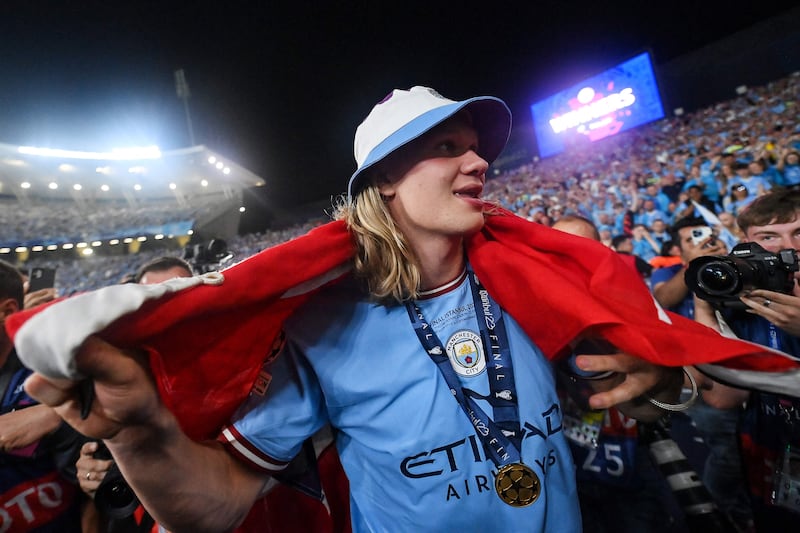 Manchester City's Norwegian striker #9 Erling Haaland, wrapped in the Norwegian flag, celebrates with the fans after winning the UEFA Champions League. AFP