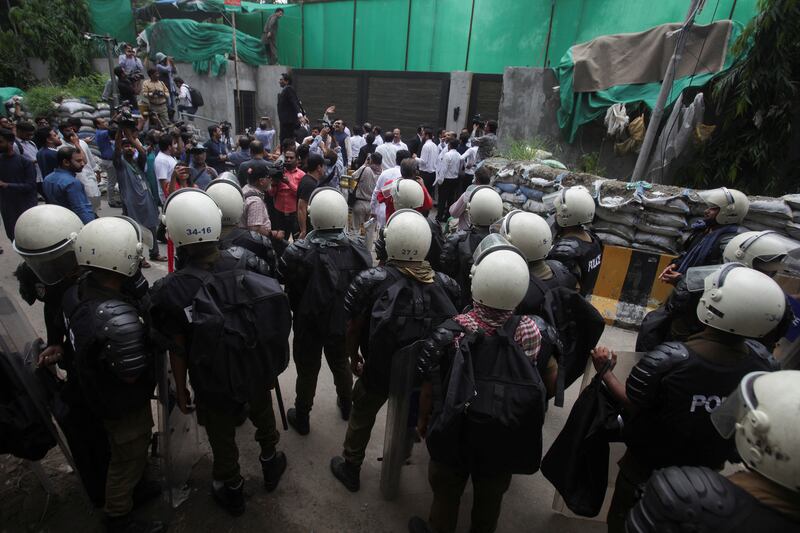 Police officers and members of the media gather outside his residence in Lahore. Reuters