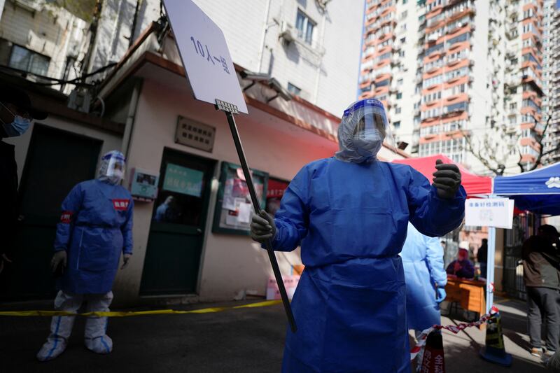 Workers in protective suits direct residents lining up for Covid testing. Reuters