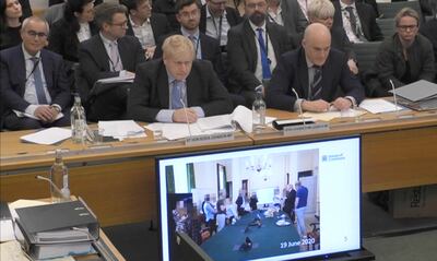 Boris Johnson looks at partygate photos on screen at Wednesday's hearing.  