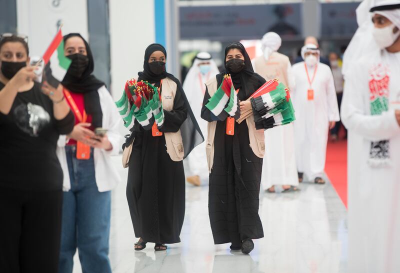 Staff at the Expo Centre Sharjah distributing UAE flags to celebrate flag day at the Sharjah International Book Fair. Ruel Pableo / The National
