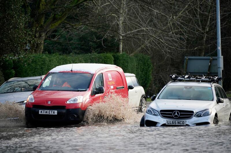 A Royal Mail van makes its way past abandoned cars in floodwater in Lymm, Cheshire. Getty Images