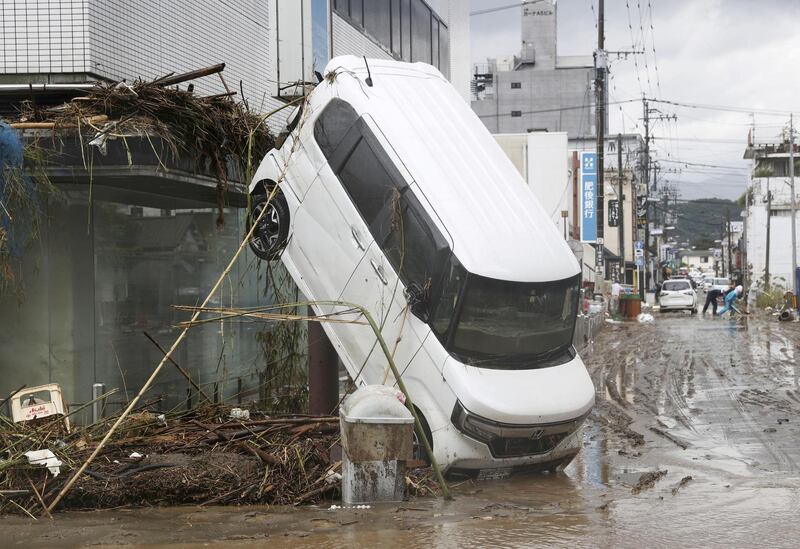 A car is left with its back wheels in the air after being swept up in heavy flooding in the southern Japanese town of Hitoyoshi, Kumamoto prefecture.  Reuters