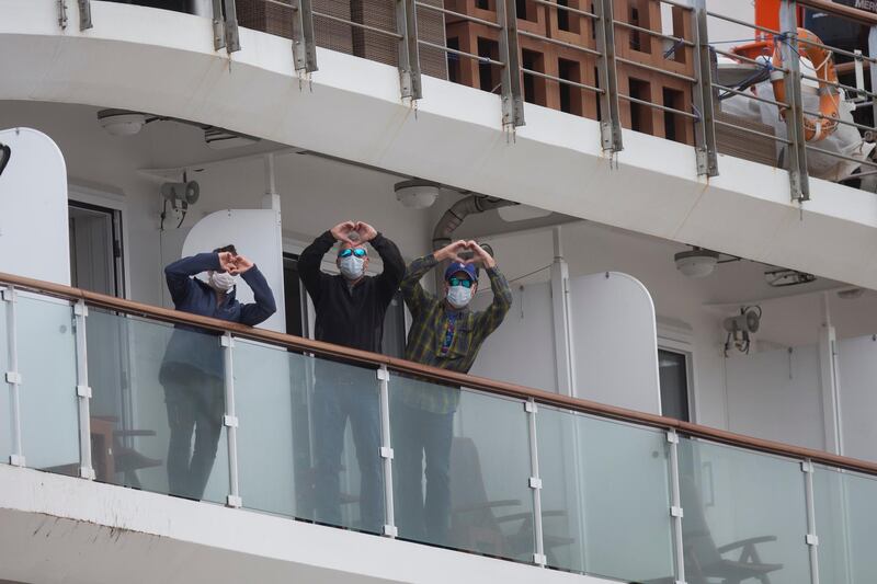 Passengers on the Australian cruise ship name Greg Mortimer gesture heart signs as they arrive to port on their way to the international airport in Montevideo, Uruguay. AP Photo