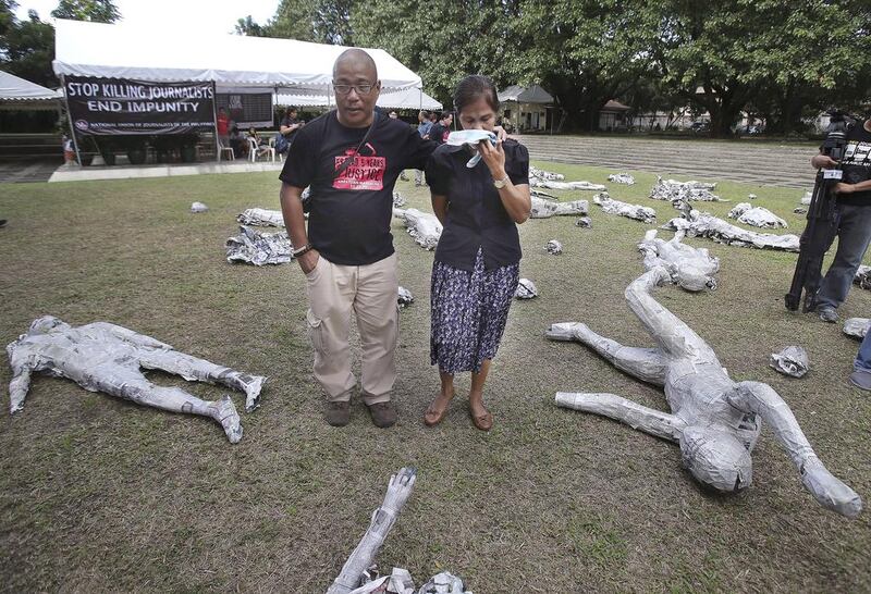 Edita Tiamzon, right, widow of slain journalist Daniel, breaks into tears as she views an art exhibit to mark the 5th anniversary of the massacre of 58 people, 32 of them journalists, in suburban Quezon city, north of Manila, Philippines on Sunday, Nov. 23, 2014. Aaron Favila/AP Photo
