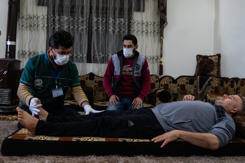 Physiotherapist Ahmed Dani provides treatment for Mr Al Sheikh in Bithynia, as colleague Mr Bardoush looks on. Mr Dani said the centre’s physios make regular tours of the area to ensure patients are not forgotten 