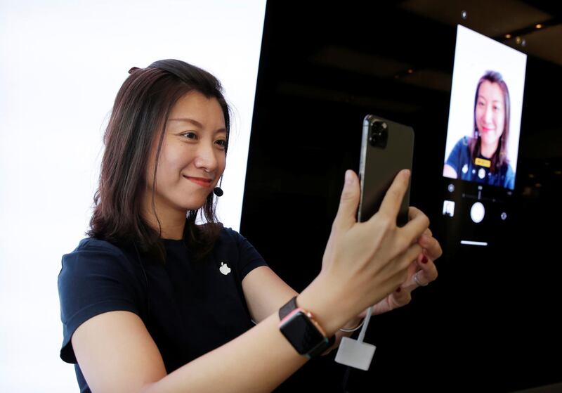 A staff member shows the new portrait shooting function for customers at the Apple Store in Beijing. Reuters