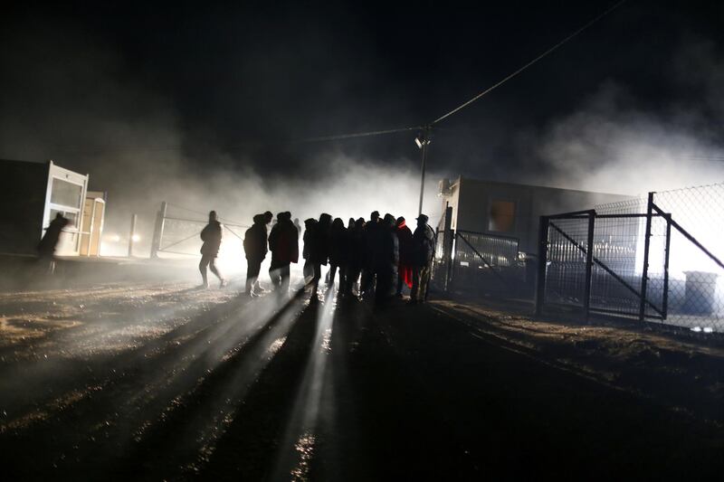 People stand in the burnt-out tent camp. Reuters