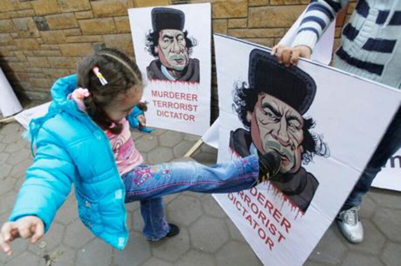 A Libyan girl kicks a poster of Libyan Leader Moammar Gadhafi, during a protest in front of the Libyan embassy in Cairo, Egypt, Monday Feb. 21, 2011. Libyan protesters celebrated in the streets of Benghazi on Monday, claiming control of the country's second largest city after bloody fighting, and anti-government unrest spread to the capital with clashes in Tripoli's main square for the first time. (AP Photo/Hussein Malla)