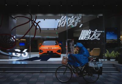 A woman rides her bicycle past a Chinese electric vehicle manufacturer Xpeng shop, in Shanghai, China. EPA