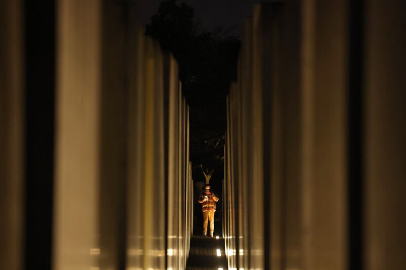 A visitor stands among illuminated columns of the Holocaust Memorial in Berlin. Getty Images