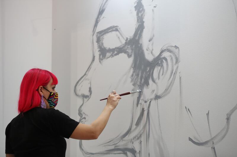 Russian-Syrian artist Dina Saadi works on her painting at the World Art Dubai fair at the Dubai World Trade Centre. EPA
