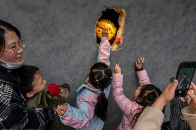 A worker wearing a furry bear paw presents roses to children through Hinichijou's hole in the wall in Shanghai, China. Getty Images