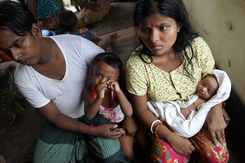 20-year-old Hindu girl, Chaw Shaw Chaw Thee (R) sits with her newborn baby, her husband and their young son at a shelter for refugees in Sittwe, on September 22, 2017. 
Chaw shaw Chaw Thee fears that twenty-three members of her family are dead, after Myanmar's army said on September 24, 2017 it had discovered a mass grave containing the bodies of 28 Hindus, including women and children, in violence-wracked Rakhine state, blaming the killings on Muslim Rohingya militants. / AFP PHOTO / Aidan JONES