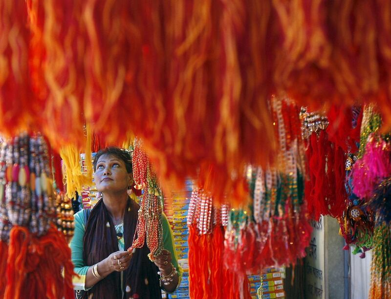 A woman buys "rakhi" or traditional Indian sacred thread, at a stall in a marketplace in Kolkata August 19, 2015. Rakhi is also the name of a Hindu festival, also known as Raksha Bandhan, during which a sister ties one or more of the sacred threads onto her brother's wrist to ask him for her protection. The festival will be celebrated across the country on August 29 this year. REUTERS/Rupak De Chowdhuri - GF10000176270