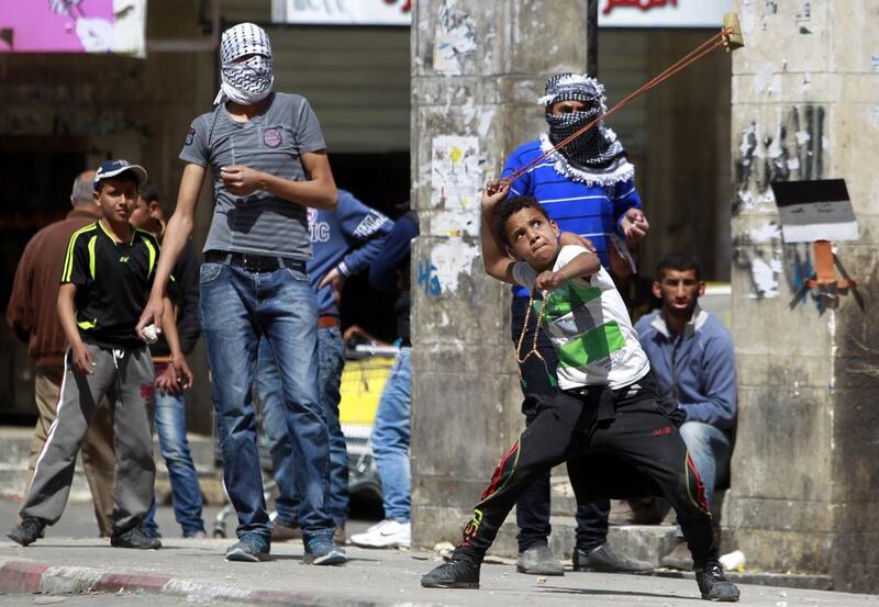 A child uses a sling to hurl rocks toward Israeli soldiers during clashes in the West Bank city of Hebron. Abed Al Hashlasmoun / EPA