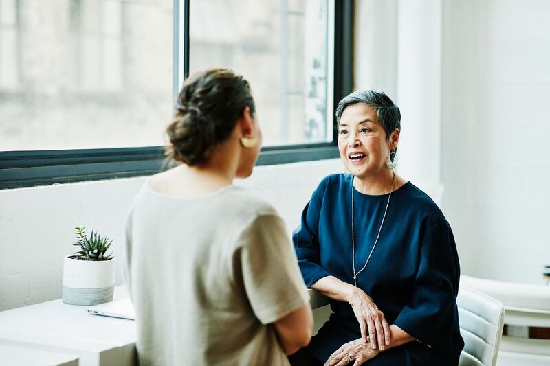 Smiling senior businesswoman in discussion with client in office conference room. Getty Images