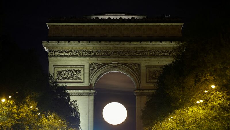 The moon rises behind the Arc de Triomphe, Paris. Reuters