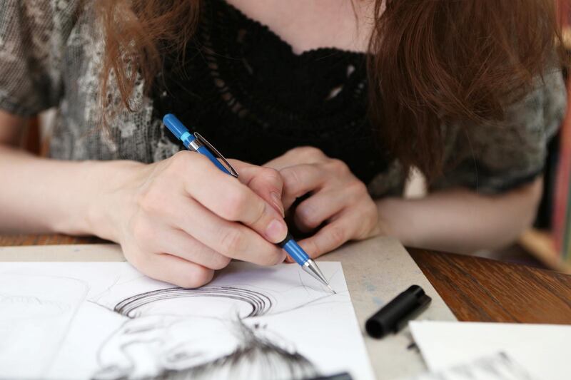 A closeup of an illustrators hands working on an illustration.