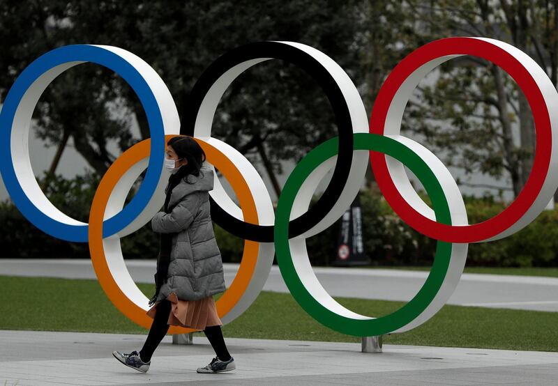 FILE PHOTO: A woman wearing a protective face mask, following an outbreak of the coronavirus disease (COVID-19), walks past the Olympic rings in front of the Japan Olympics Museum, in Tokyo, Japan March 30, 2020. REUTERS/Issei Kato/File Photo