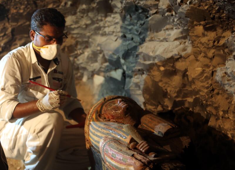 An Egyptian archaeologist works on sarcophagus at a recently discovered tomb in the Draa Abul Nagaa necropolis in Egypt. Khaled Elfiqi / EPA