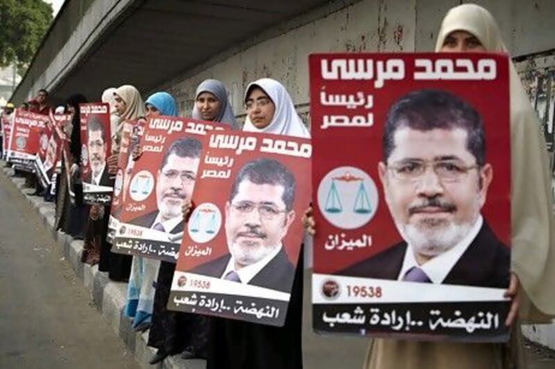 Egyptian women line up to form a human chain on Thursday as they hold posters of Muslim Brotherhood presidential candidate.