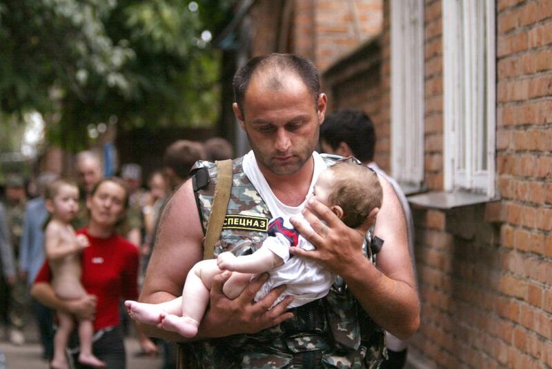 A Russian police officer carries a released baby from a school seized by heavily armed masked men and women in the town of Beslan in the province of North Ossetia near Chechnya, on September 2, 2004. Viktor Korotayev / Reuters