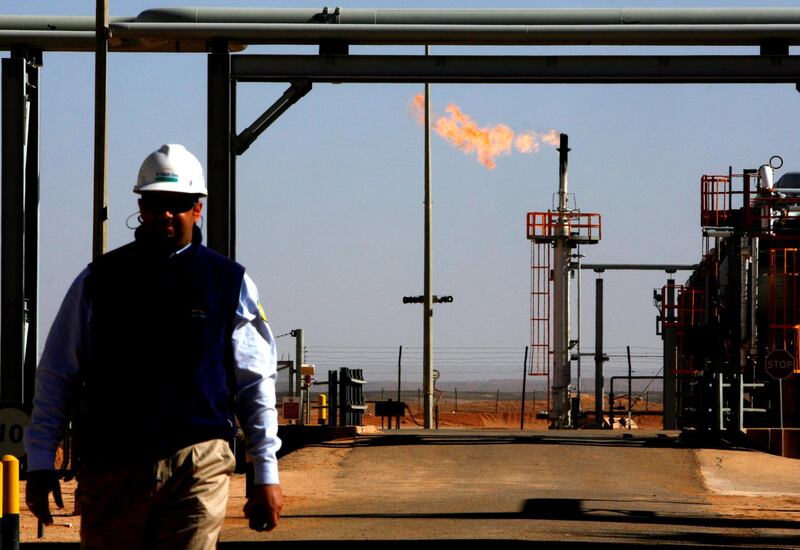 An employee walks in front of a gas flare at the In Salah Gas (ISG) Krechba Project, run by Sonatrach, British Petroleum (BP), and StatoilHydro, in the Sahara desert near In Salah, Algeria, on Sunday, Dec. 14, 2008. From produced gas, the carbon capture plant, the largest and first of its kind, removes annually the carbon dioxide emissions equivalent of 200,000 automobiles running 30,000 kilometers. The CO2 is then reinjected into a reservoir instead of the atmosphere, with the intention of storing it perpetually. Photographer: Adam Berry/Bloomberg News